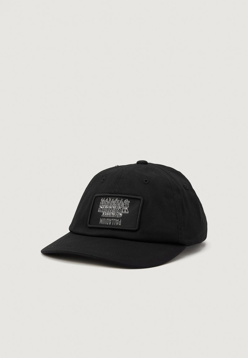 Caciulă neagră din bumbac, cu o formă rotunjită, având o etichetă rectangulară cu "Stranger Things" scrisă cu alb pe partea din față. Textură moale, cu spate ajustabil.