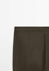 Jupe taille haute vert olive foncé avec une texture lisse et des surpiqûres visibles le long de la ceinture.