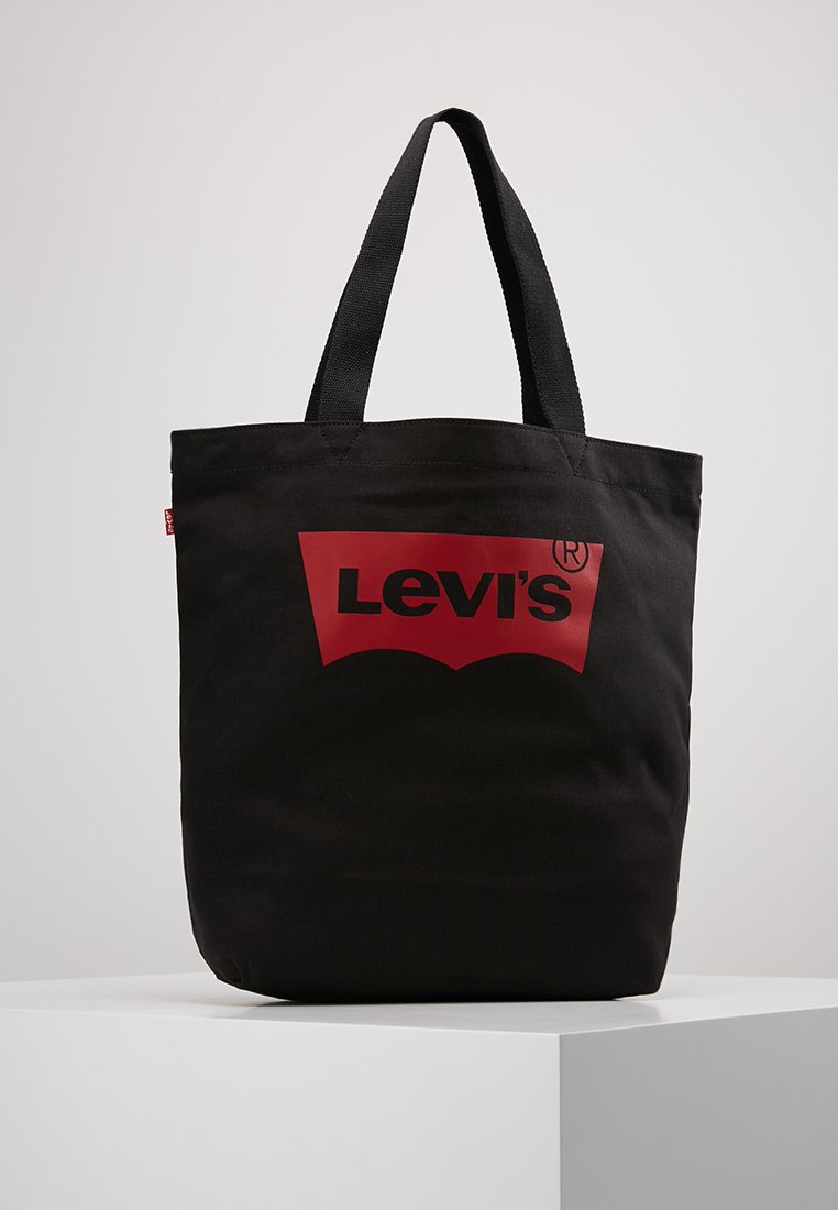 Svart canvas tote-väska med dubbla svarta handtag, med en stor röd Levi's-logotyp på framsidan och en stadig rektangulär form.