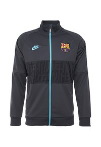 Kurtka Nike Barcelona w ciemnoszarym kolorze, z zapięciem na zamek, turkusowymi akcentami, teksturowanym czarnym panelem oraz logo drużyny na piersi.