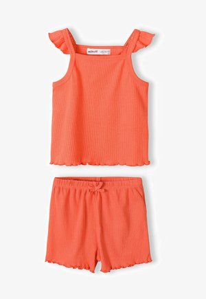 Kétrészes szett, amely egy bordázott narancssárga ujjatlan felsőből áll, fodros pántokkal és hullámos szegélyekkel, párosítva rugalmas derékú sorttal.