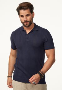 Navyblaues Polo-Shirt mit kurzen Ärmeln, strukturierter Oberfläche, zwei Knöpfen am Kragen und taillierter Passform.