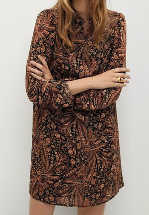 Černé šaty s dlouhým rukávem, zdobené složitým hnědým paisley vzorem, s límečkem a volnějším střihem, vyrobené z hladké látky s mírným leskem.