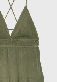 Olive green sleeveless dress with thin crisscross shoulder straps and subtle vertical metallic threads throughout fabric.