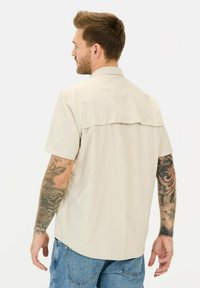 Beige Kurzarmhemd mit einer Rückenpasse, aus leichtem Material, mit lässiger Passform und genähten Akzenten.