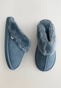 Blå ruskindstøfler med en kunstpelsmanchet, rund form og teksturerede overflader. Har kontrasterende syninger og en fleksibel gummisål.