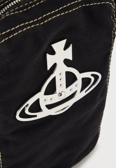 Metallisches silbernes Emblem in Form einer mit einem Kreuz versehenen Kugel mit Ringen, angebracht an schwarzem Stoff mit weißen Nähten.