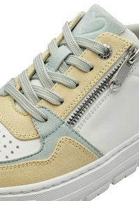 Sneaker con una combinazione di suede beige e pelle bianca. Presenta accenti azzurri, motivi testurizzati, una cerniera argentata e lacci grigi.