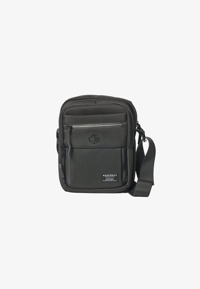 Sac bandoulière noir compact avec poche avant zippée, bandoulière réglable, logo feuille embossé et étiquette Koroshi Premium sur le panneau inférieur avant.