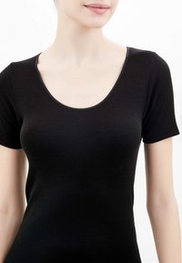 Top nero a maniche corte con scollatura rotonda, realizzato in un tessuto liscio e elastico. La texture è aderente e senza cuciture sulle spalle.