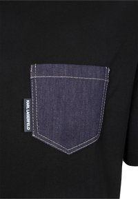 Svart T-shirt med en bröstficka i blå denim med kontrastsömmar och en etikett som säger "KARL LAGERFELD."