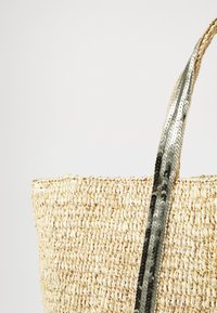 Torebka wykonana z plecionej słomy o teksturowanym, naturalnym wykończeniu; posiada metaliczny, cekinowy pasek w srebrnych i czarnych akcentach.