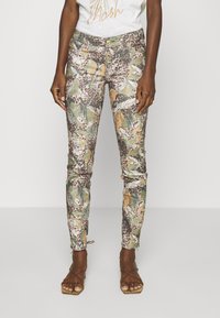 Camo-geprinte skinny broek in groen, bruin en oranje, met een gladde, licht rekbare textuur en een knoopsluiting aan de voorkant.
