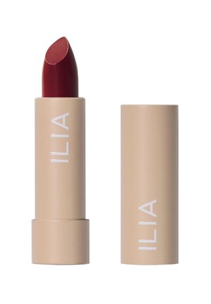 Rouge à lèvres dans un tube beige avec du texte blanc. Le raisin a une finition lisse et une pointe légèrement ronde, conçu pour une application facile.