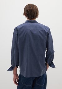 Camicia a quadri blu navy con maniche lunghe e polsini, caratterizzata da un colletto classico e orlo dritto, realizzata in tessuto leggero.