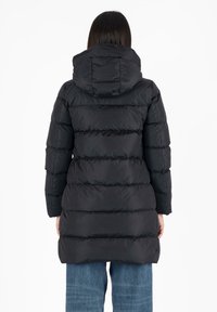 Cappotto puffer nero con cappuccio, caratterizzato da un design trapuntato e texture a coste. Arriva a metà coscia con un taglio dritto e polsini elasticizzati.