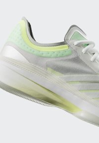 Chaussure de sport blanche et vert clair avec une tige en mesh texturé, une fermeture à lacets et une semelle épaisse et rembourrée, présentée de profil.