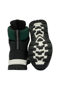 Black and green weatherproof boots with a textured upper, cushioned collar, and rugged rubber soles featuring pronounced tread patterns.