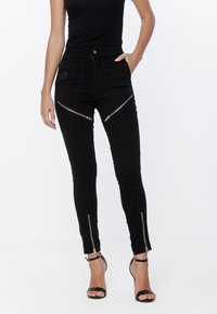 Czarne wąskie dżinsy z zamkami błyskawicznymi z przodu i na kostkach. Wykonane z denimu o dopasowanym kroju i gładkiej teksturze.