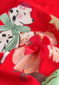 Rode stof met kleurrijke cartoonhonden met strikjes, engelenvleugels en feestelijke accessoires, vergezeld van een glimmende gouden sterdetail.