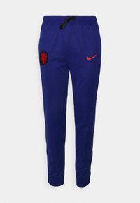 Blaue Jogginghose aus Stoff, mit einem elastischen Bund und Kordelzug, einem Löwenwappen und einem roten Nike-Logo.