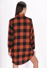 Vestito camicia a quadri rosso e nero, maniche lunghe, polsini con bottoni, orlo curvo, realizzato in morbido tessuto con vestibilità comoda. Visualizzazione del retro.