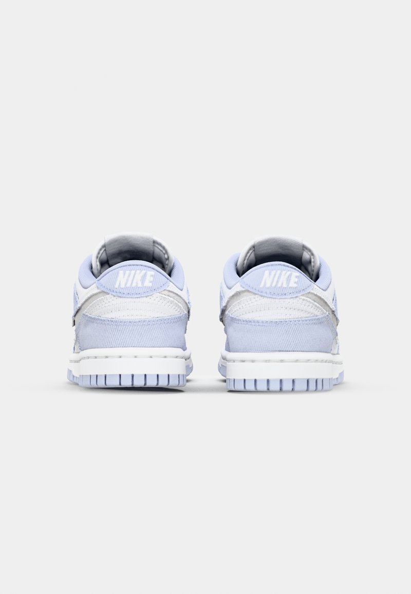 Zapatillas Nike con una parte superior de color azul claro, tejido texturizado, detalles en blanco, refuerzo en el talón y una suela de goma con un diseño de relieve.