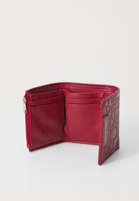 Röd läderplånbok från Armani Exchange öppen som visar flera kortfack, en dragkedja för mynt och en präglad logotyp på utsidan.