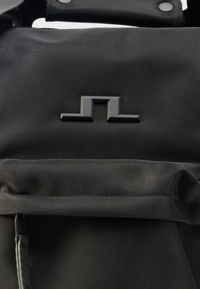 Μαύρο υφασμάτινο σακίδιο με μικρό, ανάγλυφο γεωμετρικό λογότυπο και επενδεδυμένη λαβή στερεωμένη με κουμπιά πατήματος.