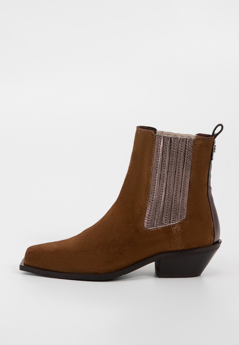 Bruine suède enkellaars met een lage zwarte hak, elastische zijpanelen en een treklip aan de achterkant, weergegeven vanaf de rechterkant op een witte achtergrond.