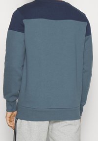 Sudadera de cuello redondo con un diseño de bloques de color azul y marino, que presenta una tela texturizada y puños y dobladillo acanalados.