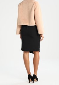 Kurtka z sztucznego futra w miękkim odcieniu różu, połączona z dopasowaną czarną spódnicą ołówkową i czarnymi szpilkami, eksponując gładkie tekstury i czyste linie.