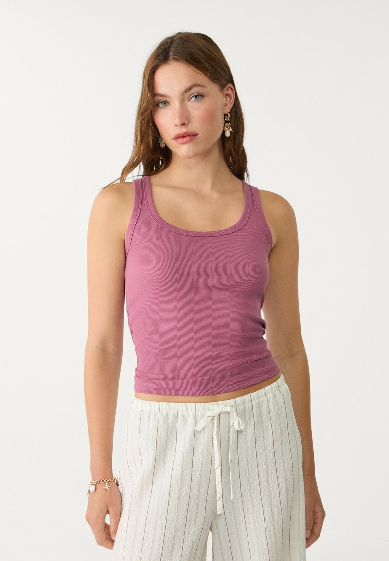 Lila, gerippte Tanktop mit breiten Trägern und rundem Ausschnitt, kombiniert mit leichten, gestreiften, weiten Hosen.
