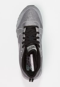 Grå Skechers-sneaker med ett texturerat mesh-övre, svarta snören och en Air-Cooled innersula. Har en flexibel sula och vadderad krage.