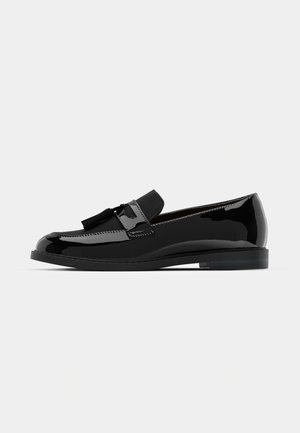 Mocasines de charol negro con tacón plano, con un acento de borlas y superficie lisa, diseñados con una puntera redondeada y costuras sutiles.