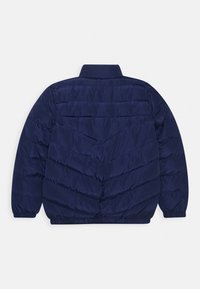 Giacca puffer blu navy con colletto alto, caratterizzata da un motivo trapuntato, polsini elasticizzati e orlo arrotondato. Materiale esterno liscio e lucido.
