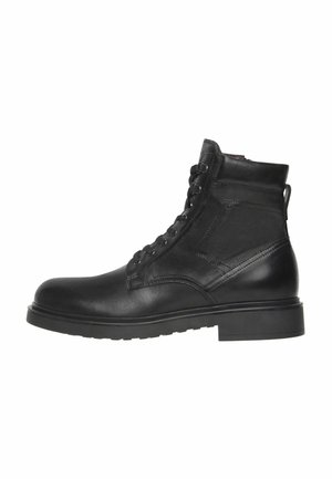 Botín de piel negra hasta el tobillo con cordones en la parte delantera, detalles de costura lateral, collar acolchado y suela de goma gruesa.