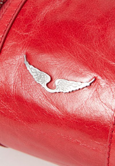 Rote Ledertasche mit strukturiertem Finish und einem dekorativen silbernen Flügel-Emblem. Glatter Reißverschluss.