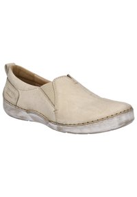 Chaussure slip-on beige en cuir doux avec panneaux élastiques sur les côtés, bout rond et semelle texturée avec une finition usée. Détails de couture visibles.