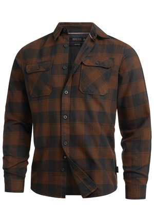 Brun og svart rutete skjorte med knapper, laget av flanell. Har to brystlommer, svarte knapper og en krage som kan brettes ned.