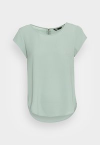 Haut vert clair à manches courtes avec un col rond et une fermeture éclair au dos. Tissu lisse avec une coupe décontractée et un ourlet arrondi.