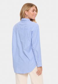 Camisa de manga larga a rayas azul y blanca con cuello abotonado, corte relajado y detalle de puño con un solo botón. Tela de algodón texturizado.