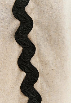 Naturalna tkanina lniana z fakturowanym, falistym czarnym wykończeniem wzdłuż jednego boku, podkreślająca kontrast i detale.