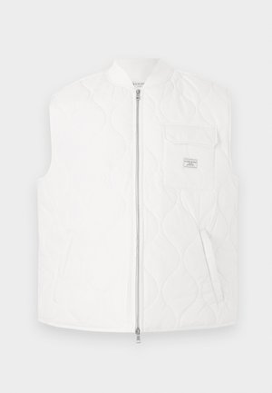 Hvit quiltet vest med høy krage, frontglidelås og brystlomme. Har et subtilt mønster og en liten merkelapp på lommen.
