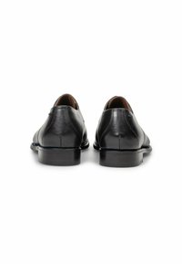 Zwarte leren schoenen met een gladde afwerking, ronde neus en lage hak. Voorzien van gestikte details en een subtiele glans. Achteraanzicht weergegeven.