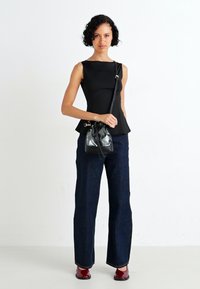Zwarte peplum top, donker gewassen flared jeans, glanzende rode hakken, en een kleine zwarte emmer tas met een transparant gedeelte.