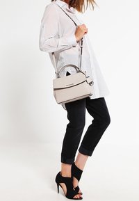 Szara, strukturalna torebka na górnej rączce z regulowanym paskiem na ramię. Wykonana z gładkiej skóry; minimalistyczny design z metalowym logo.