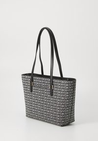 Black and gray tote bag featuring a repeating logo pattern, with two long handles and metallic accents at the base of the straps.