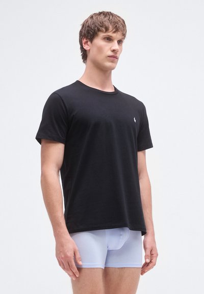 Camiseta preta de algodão com gola redonda, mangas curtas e pequeno logótipo bordado; combinada com cuecas boxer justas azul claro.