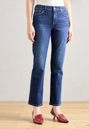 Mørkeblå denim jeans med lige ben-design, der har frontlommer og knaplukning. Båret med røde højhælede sko.